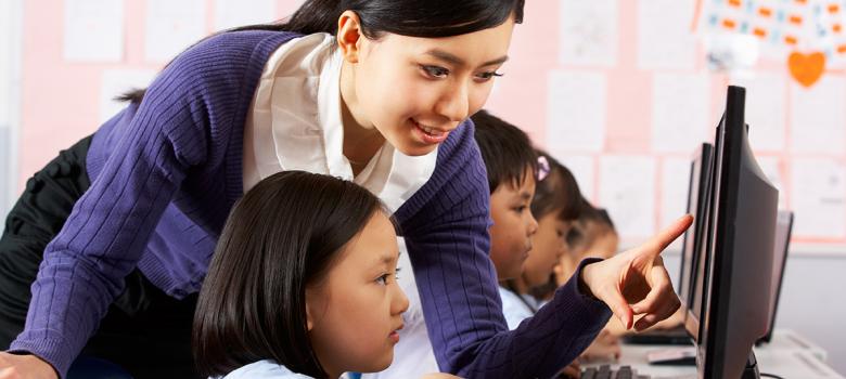 Photo: Teacher working with student at computer