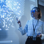 A female teacher teaches computer coding in a darkened classroom.